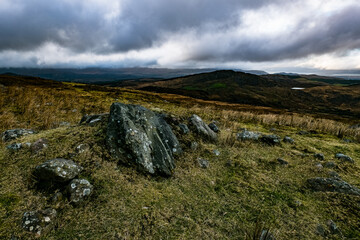 A view from a high vantage point showing rolling hills. The foreground has sparse grass and...