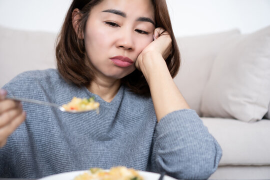 Asian woman experiencing loss of appetite and food tasteless,  boredom with eating and weight loss