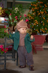 arafed toddler in a hat and jacket standing in front of a chair
