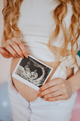 pregnant woman with ultrasound scan of baby, pink and blue balloons for genderpati