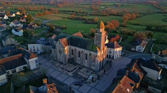 Eglise Saint-Gervais et Saint-Protais, church, Jublains town at sunset, Mayenne in France. Aerial drone pov