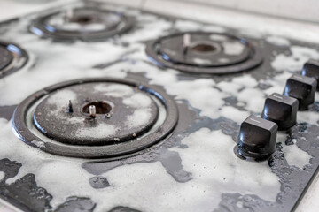 Cleaning a gas stove with kitchen utensils, household concepts, or hygiene and cleaning