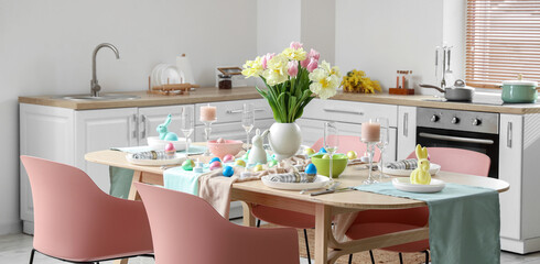 Modern interior of stylish kitchen with Easter table setting, counters and vase of flowers
