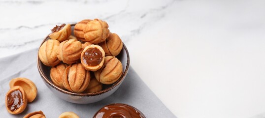 Bowl of sweet walnut shaped cookies with boiled condensed milk on white background with space for text