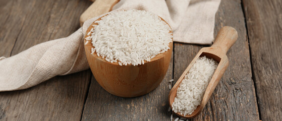 Bowl and scoop with raw rice on wooden background
