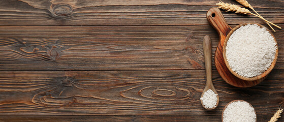 Bowls and spoon of raw rice with wheat on wooden background