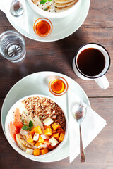 A healthy granola bowl with yogurt, mango, papaya, banana, honey, coconut flakes, and flax seeds. Served with a glass of water and a cup of coffee, creating a perfect balanced breakfast