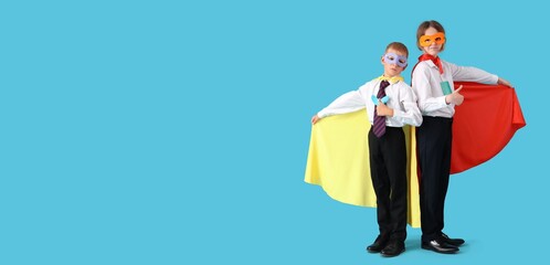 Schoolboys dressed as superheroes showing thumbs-up on light blue background with space for text