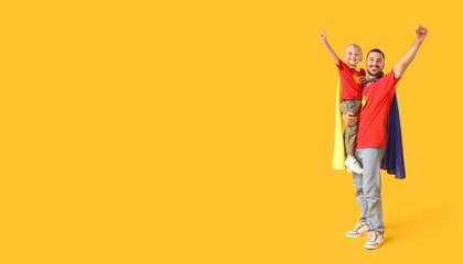 Happy father and his little son dressed as superheroes on yellow background with space for text