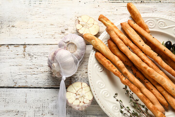 Plate with tasty Italian Grissini on light wooden background, closeup