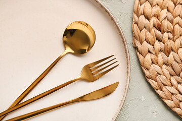 Plate with golden cutlery on grey background