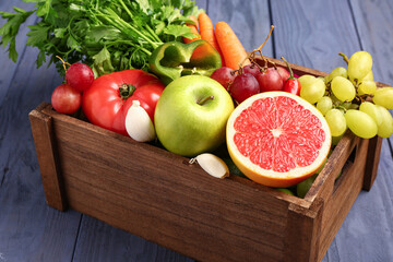 Box with different fresh fruits and vegetables on blue wooden background