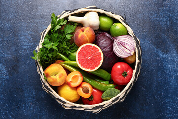 Wicker bowl with different fresh fruits and vegetables on blue background