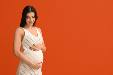 Happy pregnant woman on orange background