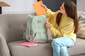 Little schoolgirl with copybook in backpack at home