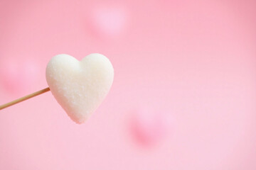 Small heart shaped object on pastel pink bokeh background
