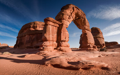 Fototapeta premium Iconic desert rock arch with vibrant red sandstone formations under a deep blue sky creating a breathtaking natural wonder
