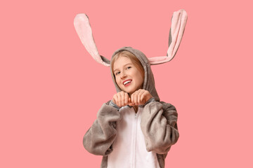 Fototapeta premium Beautiful young happy woman in bunny costume and hands holding ears on pink background. Easter celebration