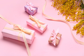 Gift boxes and mimosa on pink background