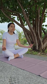 Doing siddhasana yoga pose under a tree at the park