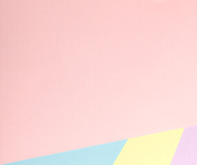 A pastel abstract background with a geometric arrangement of multicolored paper in soft tones, including pink, yellow, blue, and lavender. The minimalist design emphasizes simplicity, texture, and