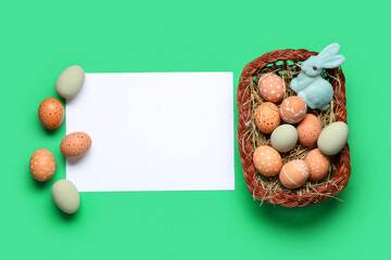 Easter bunny, painted eggs and blank greeting card on green background. Top view