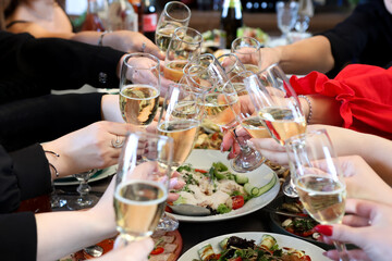The girls make a toast with glasses of champagne at the festive table.