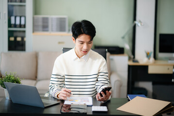 Young business man working at office with laptop, tablet and taking notes on the paper..