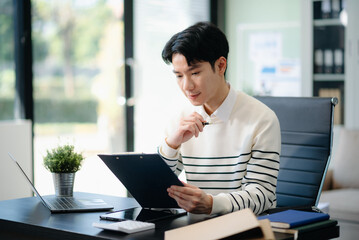Young handsome man typing on tablet and laptop while sitting at the working table