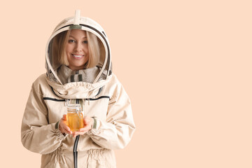 Female beekeeper with jar of sweet honey on beige background
