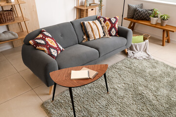Interior of living room with black sofa, coffee table and cushions