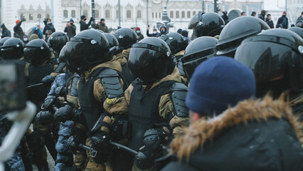 Riot police team with tinted visor on helmets. Policeman officers in rushing attack of protesting crowd on streets. Protesters on demonstration under police units offensive. Pushing enforcers line.