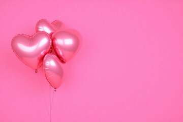 four shiny metallic pink heart shaped balloons on solid pink