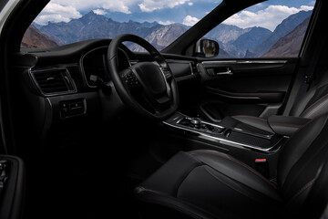 A black car with a steering wheel and a mountain in the background