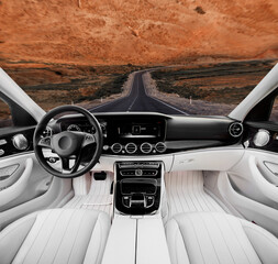 A car is driving down a road with a desert in the background