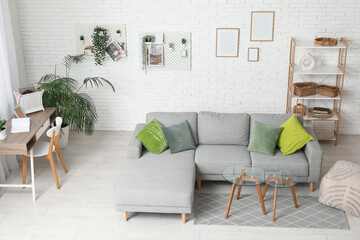 Living room with grey sofa, workplace, coffee table and pegboard