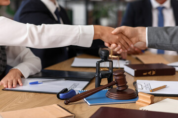 Lawyers shaking hands at table in office, closeup
