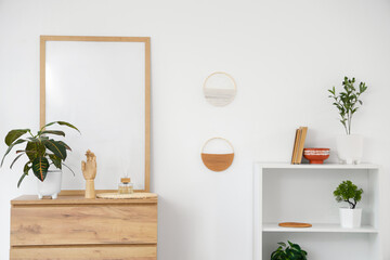 Interior of light living room with commode, shelf unit and frame