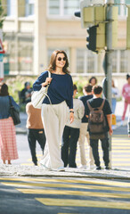 Outdoor portrait of beautiful young woman crossing the road on a zebra, urban lifestyle