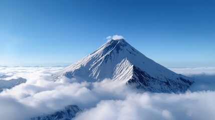A majestic mountain stands tall, its snow-covered peak soaring above a sea of fluffy clouds. The bright blue sky enhances the tranquil beauty of this natural wonder during daylight