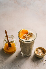 Warmer Porridge mit Orange und Honig in einem Trinkglas auf einem grauen Tisch. Gesundes Frühstück.