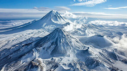 Majestic snow-capped volcanoes of Kamchatka under a clear blue sky with faint clouds swirling around