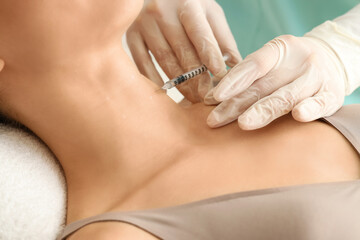Young woman receiving injection in her neck on couch at cosmetologist's office, closeup
