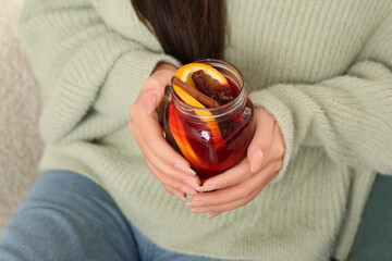 Beautiful young woman with cup of hot mulled wine at home, closeup