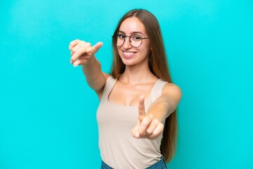 Fototapeta premium Young caucasian woman isolated on blue background pointing front with happy expression