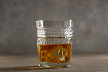 Glass of cold rum on table against grey background. Closeup