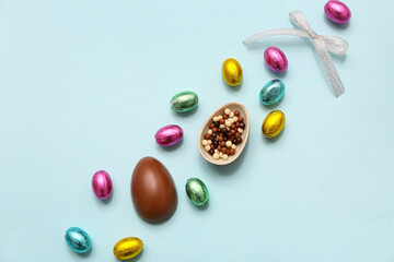 Chocolate Easter eggs in foil with candies on blue background