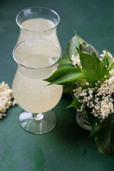 Carbonated elderflower drink. Flower summer kvass in glasses. Sparkling homemade hugo water. Green leaves