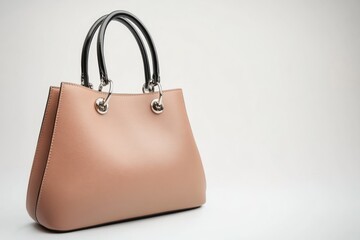 A tan purse with a black handle sitting on a white background