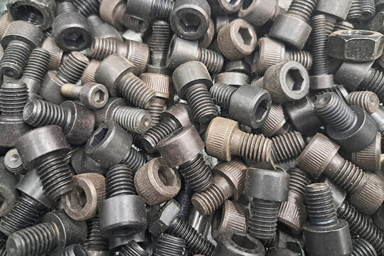 Large black metal screws texture. Industrial steel bolts with deep threading. Heavy duty construction pattern. Rugged mechanical hardware background.